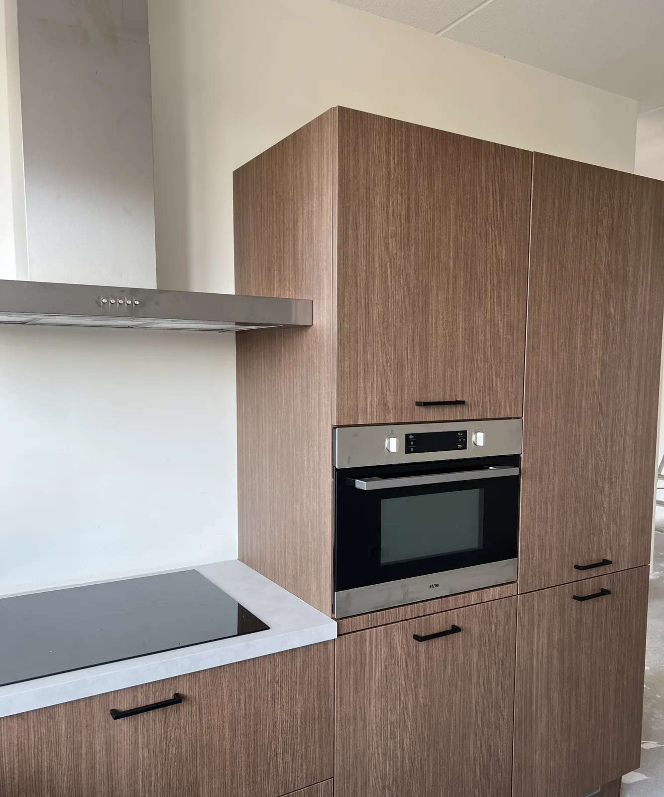 L-keuken met fronten in notenhoutlook folie en aanrechtblad in betonlook
