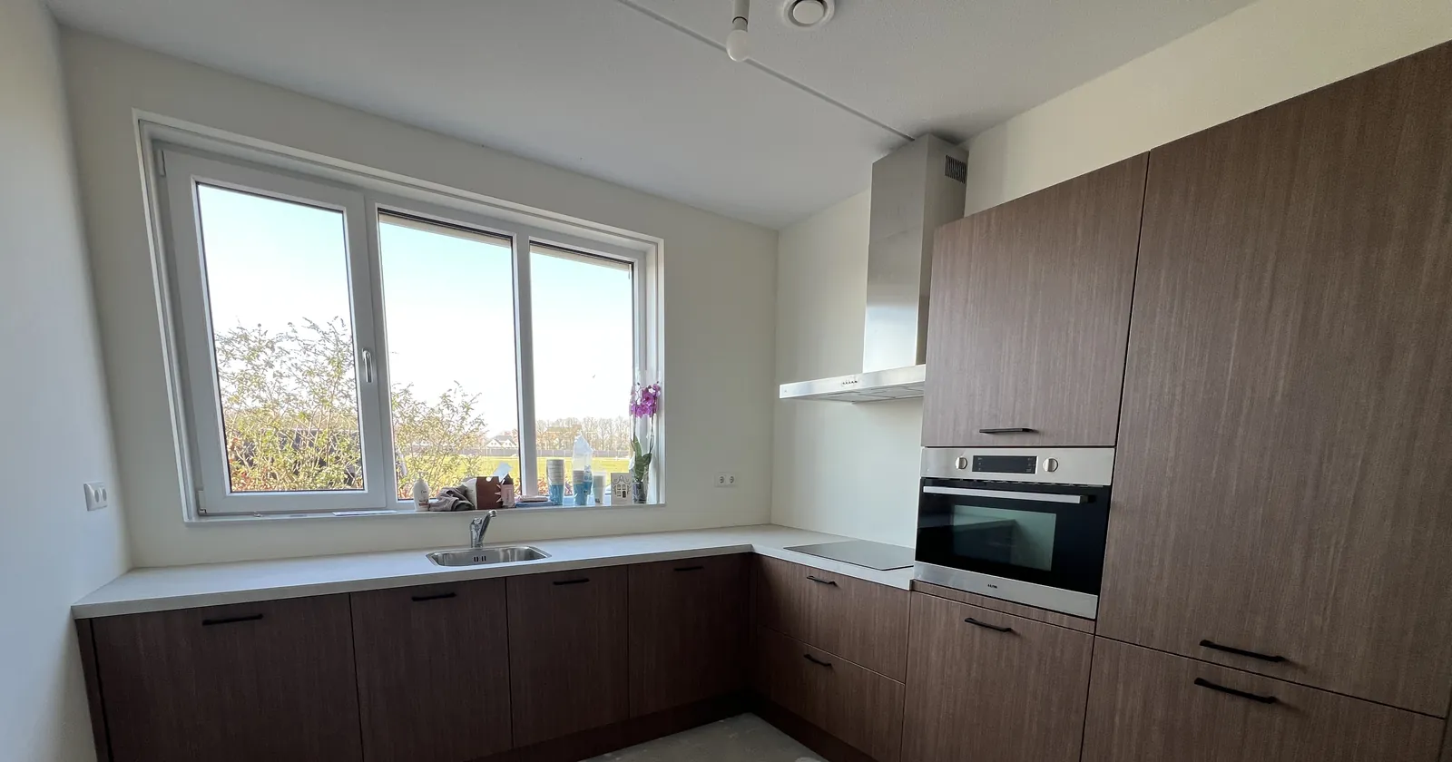 L-keuken met fronten in notenhoutlook folie en aanrechtblad in betonlook, foto 3